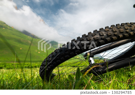 Close-up of rear wheel of mountain bike against rocky mountains in clouds. Copy space Close-up of rear wheel of mountain bike against rocky mountains in clouds. Copy space 130294785