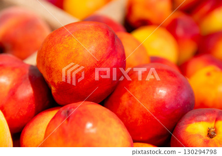 Close-up a lot of fresh red yellow colored peaches on market stall or in groceries shop area. Nectarines background. Fruit food background. Selective focus Close-up a lot of fresh red yellow colored peaches on market stall or in groceries shop area. Nectarines background. Fruit food background. Selective focus 130294798