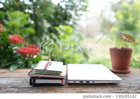 Folded Laptop and notebook, black coffee cup, working in the garden 130295182