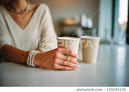 A woman is holding two cups of coffee in her hands 130295236