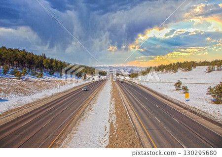 Highway in Rocky Mountains with snow and dramatic sky 130295680
