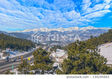 Scenic highway with Rocky Mountains peaks and pine forest 130295683