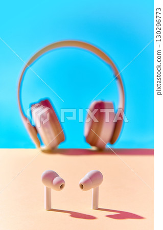 Modern earbuds with blurred retro headphones in background 130296773