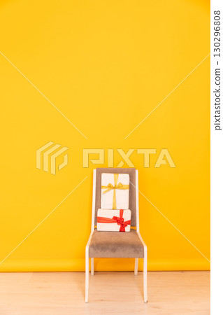 chair with gift in the interior of a yellow orange room chair with gift in the interior of a yellow orange room 130296808
