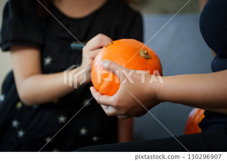 Halloween Fun. Close-up of hands decorating a pumpkin with a marker. 130296907