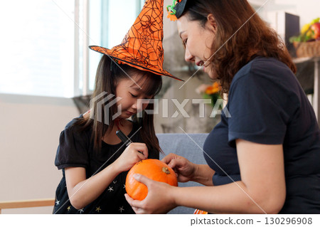 Halloween Crafting. Child and mother decorating pumpkins together. 130296908