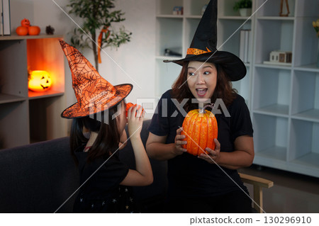 Halloween joy: mother and daughter sharing excitement with pumpkins and festive hats Halloween joy: mother and daughter sharing excitement with pumpkins and festive hats 130296910