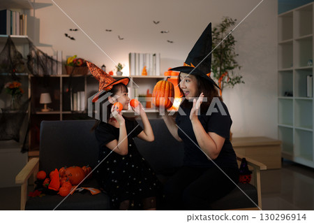 Halloween bonding. Mother and daughter sharing joy with pumpkins in festive hats. Halloween bonding. Mother and daughter sharing joy with pumpkins in festive hats. 130296914