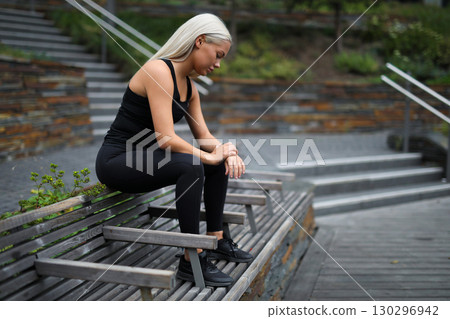 Young woman resting on a bench outdoors in a modern urban park Young woman resting on a bench outdoors in a modern urban park 130296942