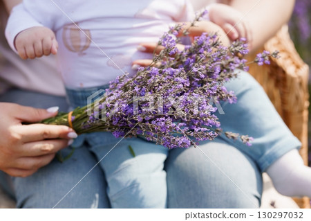 Mother and Baby Holding Lavender Bouquet in Sunlit Field, Gentle Parental Care, Pastel Colors, Natural Lifestyle Photography. 130297032