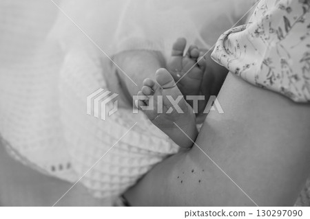 Newborn Baby Feet Close Up on Mother's Lap: Black and White Photo Showing First Tender Moments, Soft Texture, Skin Tone, Parenthood, and Love. 130297090