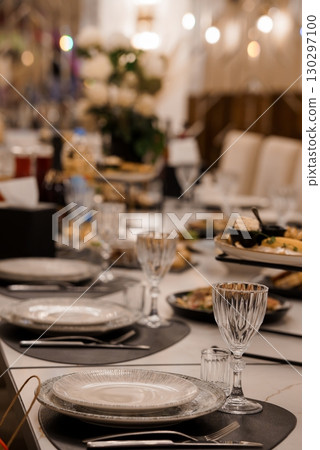 Elegant Wedding Reception Table Setting with Crystal Glasses and Gold Accents, Luxurious Dinner Scene, Warm Lighting and White Decor 130297100