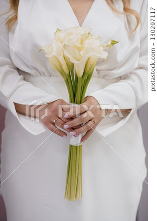 Elegant Bride Holding Cream Calla Lily Bouquet: Wedding, White Dress, Romance, Luxury, Floristry, Close-Up, Celebration, Minimalist Style. Elegant Bride Holding Cream Calla Lily Bouquet: Wedding, White Dress, Romance, Luxury, Floristry, Close-Up, Celebration, Minimalist Style. 130297117