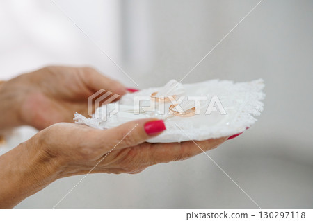 Delicate Wedding Rings on Lace Pillow Held by Mature Woman, Golden Bands, Symbolic Love, Elegant White, Close-up Ceremony Detail. Delicate Wedding Rings on Lace Pillow Held by Mature Woman, Golden Bands, Symbolic Love, Elegant White, Close-up Ceremony Detail. 130297118