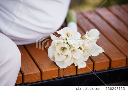 Elegant White Calla Lilies Bouquet on Wooden Park Bench - Wedding, Romance, Still Life, Celebration, Natural Light, Soft Focus, Floral Arrangements Elegant White Calla Lilies Bouquet on Wooden Park Bench - Wedding, Romance, Still Life, Celebration, Natural Light, Soft Focus, Floral Arrangements 130297133