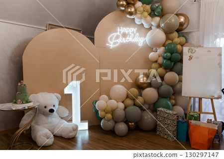 First Birthday Celebration Backdrop with Balloon Garland, Teddy Bear, and Neon Sign. Green, Gold, and White Party Decor for Baby's Milestone. First Birthday Celebration Backdrop with Balloon Garland, Teddy Bear, and Neon Sign. Green, Gold, and White Party Decor for Baby's Milestone. 130297147