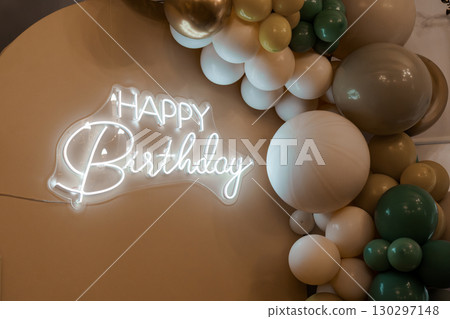 Modern Beige Balloon Garland Backdrop with Neon "Happy Birthday" Sign for Celebration and Party Decor, Warm Toned Event Setup 130297148