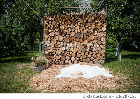 Rustic Outdoor Nap Scene: Log Wall Backdrop, White Blanket, Straw Bed, Summer Garden, Natural Texture, Relaxing Lifestyle, Tranquility, Hay Field. 130297153