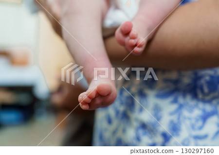 Tender Baby Feet Held by Parent on Blue Fabric, Close-Up Focus on Delicate Skin, Soft Lighting, Infant Care Concept. 130297160