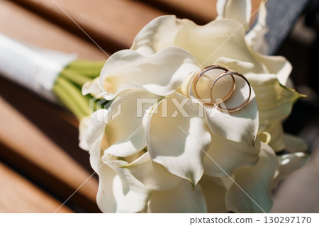 Wedding Rings on White Calla Lilies Bouquet, Golden Bands, Romance, Close-Up, Sunlight, Bridal Flowers, Celebration, Love, Elegant Style Wedding Rings on White Calla Lilies Bouquet, Golden Bands, Romance, Close-Up, Sunlight, Bridal Flowers, Celebration, Love, Elegant Style 130297170