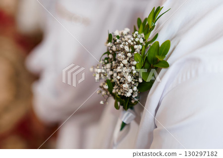 Wedding Boutonniere Close-Up: Delicate White Babys Breath and Greenery on Groom's Lapel, Formal Attire, Blurred Background, Soft Lighting 130297182