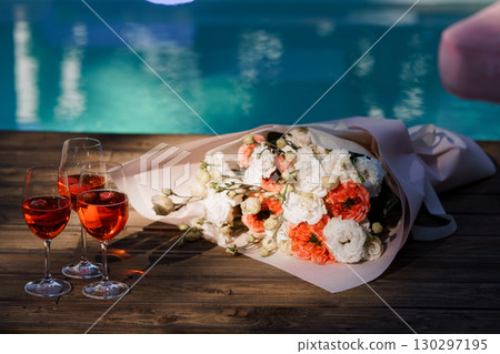 Romantic Poolside Celebration with Bouquet and Wine Glasses. Sunset, Warm Colors, Love, Special Occasion, Luxury Lifestyle, Flowers Romantic Poolside Celebration with Bouquet and Wine Glasses. Sunset, Warm Colors, Love, Special Occasion, Luxury Lifestyle, Flowers 130297195