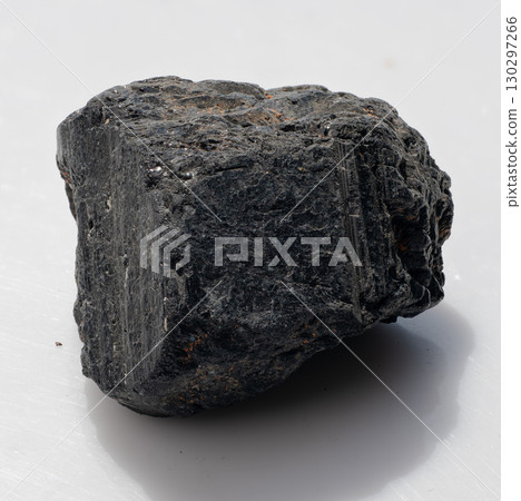Raw Black Tourmaline Crystal Specimen Isolated on White. Dark Mineral with Striations, Rough Texture, Protective Stone, Natural Gemstone Raw Black Tourmaline Crystal Specimen Isolated on White. Dark Mineral with Striations, Rough Texture, Protective Stone, Natural Gemstone 130297266