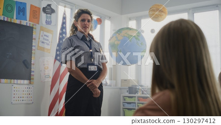 American Female TSA Security Officer Explaining Safety Rules to Young Students at Elementary School 130297412