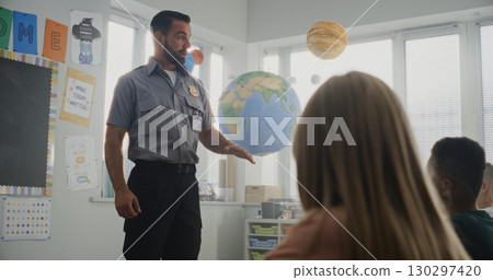Male Policeman Giving Lecture to Curious Primary School Students About Safety Rules 130297420