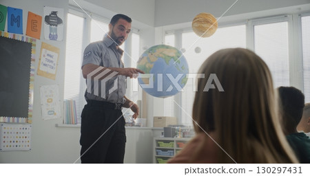 Male Policeman Giving Lecture to Curious Primary School Students About Safety Rules 130297431