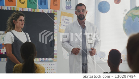 Doctor Visiting Classroom, Giving Lecture to Curious Primary School Students About Health and Hygiene Doctor Visiting Classroom, Giving Lecture to Curious Primary School Students About Health and Hygiene 130297484