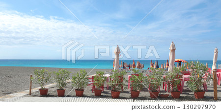 Beach umbrellas and sun loungers by sea Lacoste brand. Summer, vacation in Liguria, Italy. Background for text. 130297970