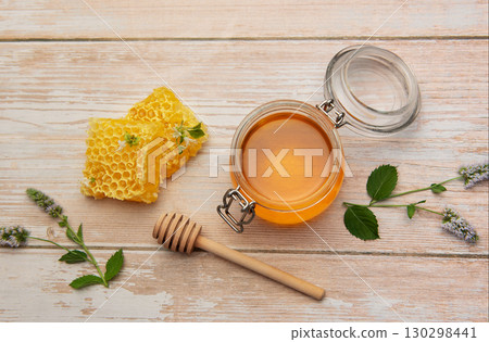 Honeycomb, jar of honey and wooden honey dipper on rustic table 130298441