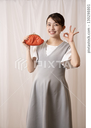 A smiling eight-month pregnant woman holding a red wallet A smiling eight-month pregnant woman holding a red wallet 130298801