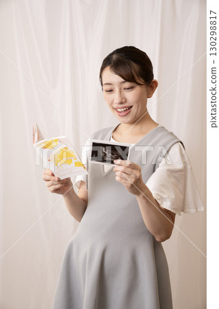 一名孕婦正在查看母嬰健康手冊和超音波影像 130298817