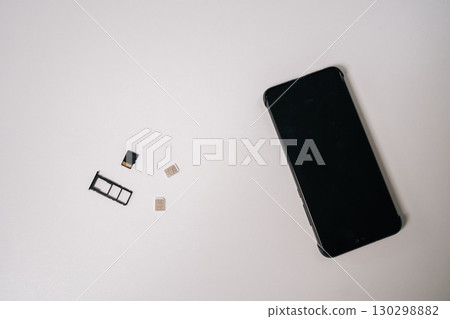 Sim cards and memory card positioned near sleek smartphone on white surface, representing mobile technology connectivity and potential device customization, nobody. Concept of modern communication 130298882