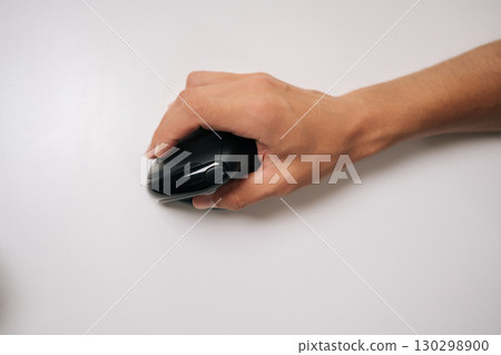 Close-up top view of male hand holding vertical ergonomic mouse on white background, highlighting design and promoting comfortable computer use for work or gaming, copy space. Close-up top view of male hand holding vertical ergonomic mouse on white background, highlighting design and promoting comfortable computer use for work or gaming, copy space. 130298900