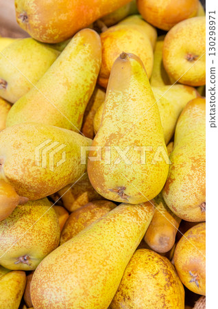 A pile of ripe juicy yellow pears displayed for sale on a supermarket vegetable counter. Demonstration of organic vegetarian and healthy food. Close-up. A pile of ripe juicy yellow pears displayed for sale on a supermarket vegetable counter. Demonstration of organic vegetarian and healthy food. Close-up. 130298971