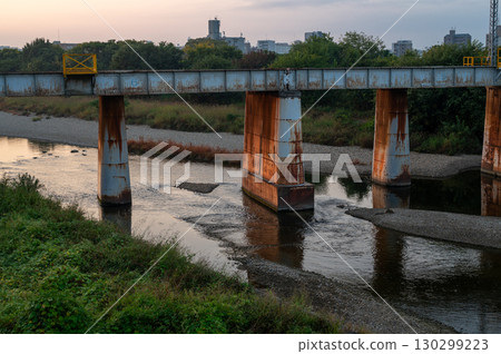 A rusty iron bridge over a river and sunset scenery 130299223