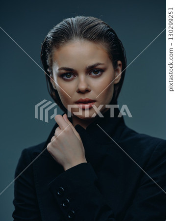 Portrait of a serious young woman with wet hair in black clothing against a dark background 130299251