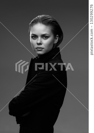 Black and white portrait of a serious woman with slicked-back hair wearing a dark coat on a gray background Black and white portrait of a serious woman with slicked-back hair wearing a dark coat on a gray background 130299276