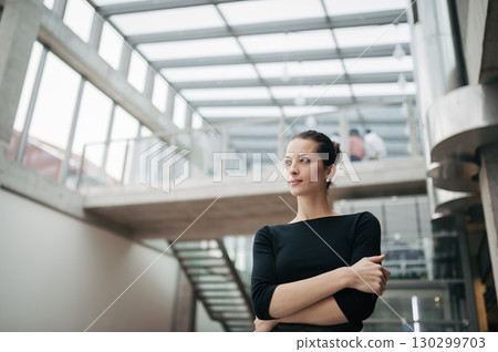 Portrait of young businesswoman standing in modern openspace office building. 130299703