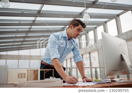 Young businessman, engineer working in office, working on plan or technical document. Young businessman, engineer working in office, working on plan or technical document. 130299705