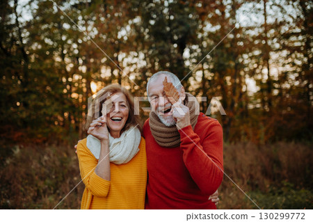 Seniors holding fallen leaves in front of eye Seniors holding fallen leaves in front of eye 130299772