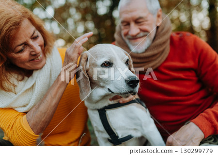 Elderly man and woman walking their dog in nature on autumn day. 130299779