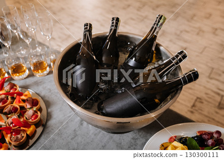 Chilled champagne bottles in ice bucket on elegant catering table at celebration event Chilled champagne bottles in ice bucket on elegant catering table at celebration event 130300111
