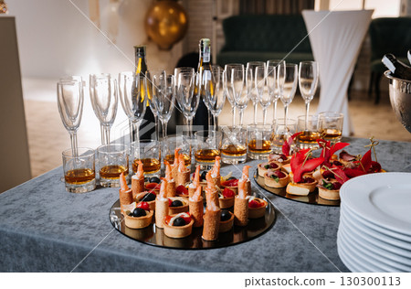 Elegant gourmet appetizers and champagne glasses set for a festive celebration Elegant gourmet appetizers and champagne glasses set for a festive celebration 130300113