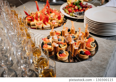 Elegant catering table with gourmet appetizers, whiskey shots and champagne glasses Elegant catering table with gourmet appetizers, whiskey shots and champagne glasses 130300115