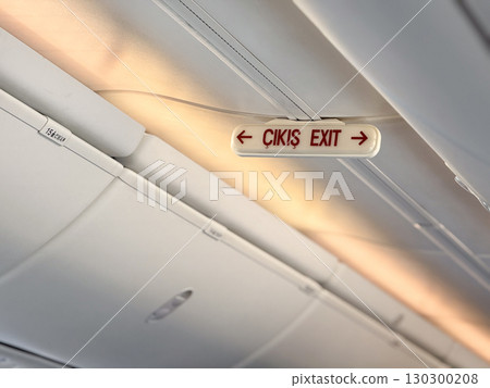 Airplane exit sign with bilingual marking. Safety, navigation, and emergency direction inside passenger aircraft. 130300208