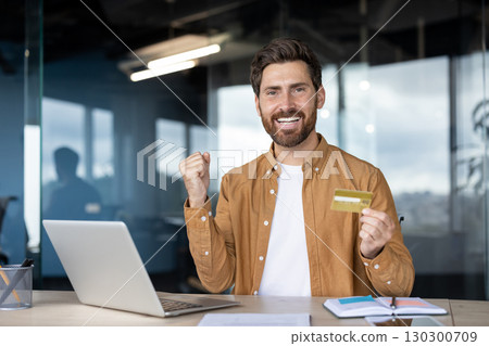Cheerful businessman is expressing his excitement after a successful online purchase using his credit card, highlighting the ease and convenience of modern e-commerce 130300709